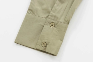 Close-up of olive green poplin shirt cuffs featuring fine stitching and double-button closure