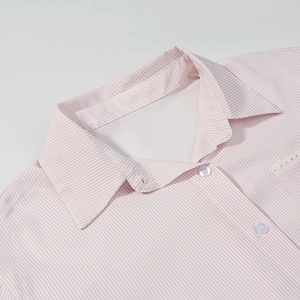 Detail eines rosa gestreiften Hemdkragens mit feiner weißer Spitze und weißen Knöpfen