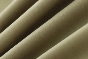 Macro texture of olive poplin fabric showing fine weave and soft brushed finish on shirt