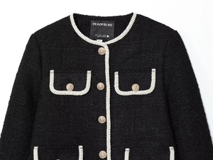 Detail of tweed jacket with contrast braid trim and embossed gold lion buttons