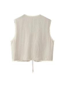 Detail of floral lace trim and drawstring ties on a beige cotton cropped vest