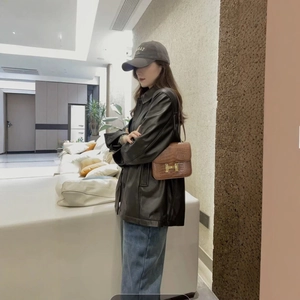 Chic women's black faux leather jacket paired with denim jeans and a stylish shoulder bag