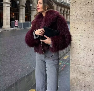 Close-up of fluffy burgundy faux fur jacket paired with stylish grey jeans and chain bag