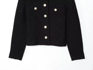 Detail of black tweed jacket featuring gold embossed metal buttons and woven texture