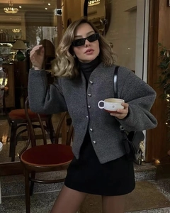 Detail view of charcoal grey wool jacket with round neck and metallic button accents