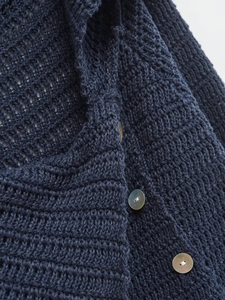 Detail of navy blue crochet knit cardigan with white shell buttons and hollow pattern