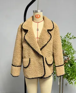 Détail de la veste en polaire camel avec bords brodés ondulés noirs et texture chaude