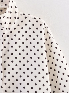 Detail shot of the collared polka dot blouse showing woven texture and shoulder stitching