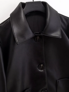 Detail of black faux leather jacket featuring a lapel collar and round buttons
