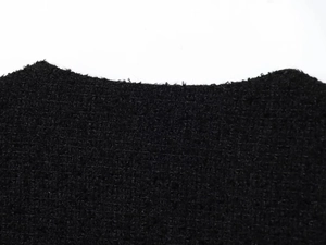 Detail view of premium black tweed fabric texture with intricate woven edge craftsmanship