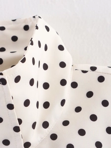 Close-up of neckline stitching and texture on white black polka dot jacket top