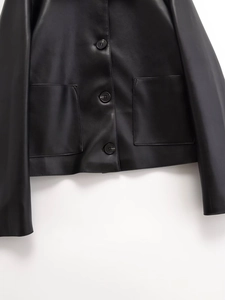 Detail of black faux leather jacket featuring button closure and two large patch pockets
