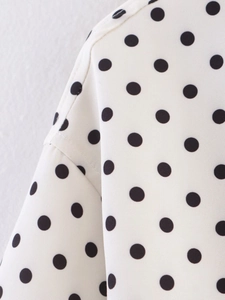 Close-up of high-quality white fabric with black polka dots and detailed stitching