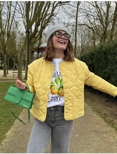 Detail shot of a yellow quilted jacket paired with a vibrant green luxury leather handbag