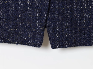 Detail view of navy tweed jacket featuring shimmering sequins and a refined side slit hem