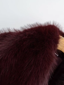 Detailed macro view of soft burgundy faux fur texture on a cropped jacket
