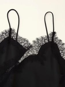Detail of black lace trim and satin fabric on women's asymmetrical camisole dress