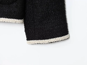 Detail of tweed fabric texture with decorative off-white braided edge on black jacket