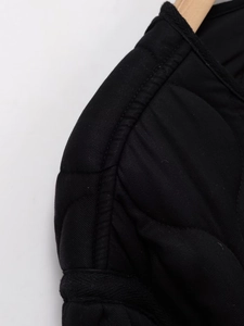 Detailed close-up of a black quilted cotton jacket featuring premium twill fabric texture