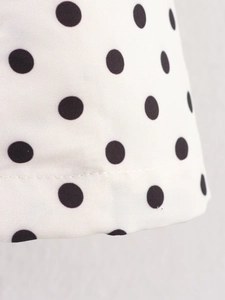 Macro detail of white fabric with black polka dots featuring precise stitching lines