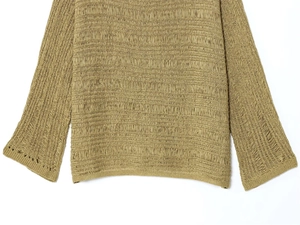 Detailed close-up of olive green knit fabric texture with hollow-out pattern and wide cuff