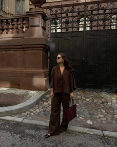 Détail d'une femme portant un ensemble marron col en V et un pantalon large en ville