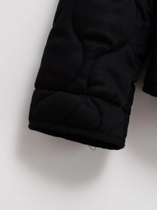 Detail of black onion-quilted jacket cuff showing high-quality stitching and fabric texture