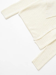 Close-up of off-white crochet knit cardigan with hollow square texture and white buttons