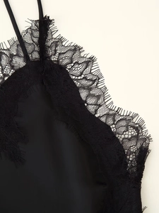 Detailed close-up of exquisite eyelash lace trim and matte satin on a black camisole dress