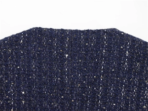 Detail of dark blue tweed fabric with gold sequins on a minimalist collarless neckline