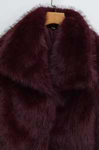 Close-up of deep wine red faux fur coat showing thick plush texture and luxury lapels