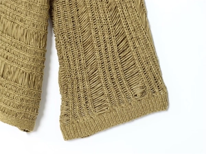 Detailed macro view of olive green knit fabric with distressed cut-outs and ribbed textures