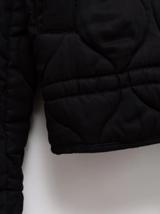 Detail of black quilted jacket cuff showing durable twill texture and elastic edge