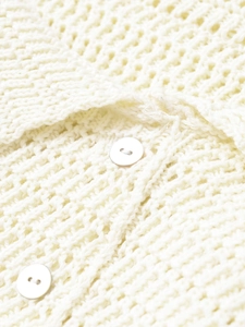 Detail of off-white chunky knit texture and round matching buttons on the sleeve cuff