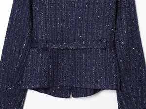 Detail of dark blue tweed jacket with sparkling sequins and decorative waist loops