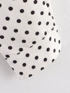Close-up of sleeve cuff on a polka dot jacket with fine stitching and fabric detail