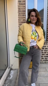 Detail of yellow quilted jacket paired with a green crossbody bag and lemon graphic tee