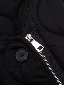 Macro shot of silver metal zipper and resin button on black quilted cotton jacket