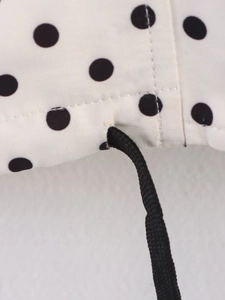 Detail of white polka dot fabric with black drawstring and premium stitching quality