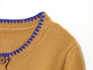 Macro view of brown knit cardigan featuring blue crochet lace neckline and resin button