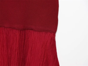 Macro view of burgundy knitted texture spliced with pleated fabric on a long dress