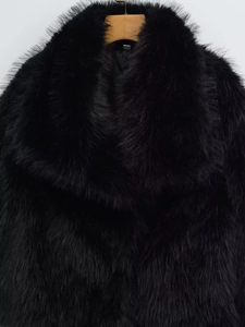 Detailed close-up of premium black faux fur jacket with wide lapels on a wooden hanger