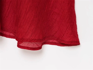 Macro shot of red pleated fabric texture and delicate hem stitching on the dress