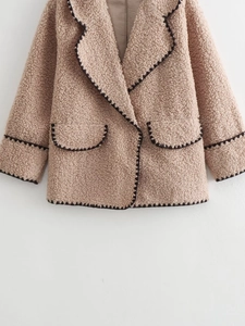 Detail of beige fleece coat featuring black contrast stitching and large lapel collar
