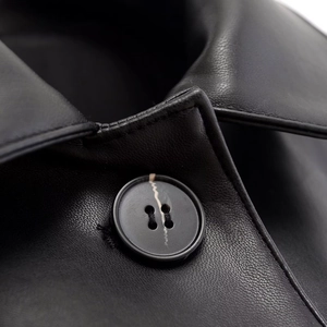 Close-up of black faux leather jacket collar with detailed stitching and resin button