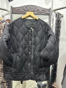 Detail of black wave quilted jacket with unique round buttons and side zipper closure