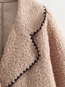 Close-up of lapel detail on beige teddy coat with black and white wavy trim