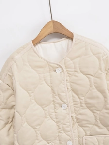 Close-up of wavy quilted texture and woven edge detail on apricot round neck jacket