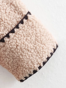 Close-up of beige fleece jacket fabric with black zigzag decorative edge contrast detail
