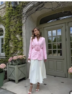 Détail du blazer rose avec ceinture fleurie 3D et jupe plissée blanche élégante